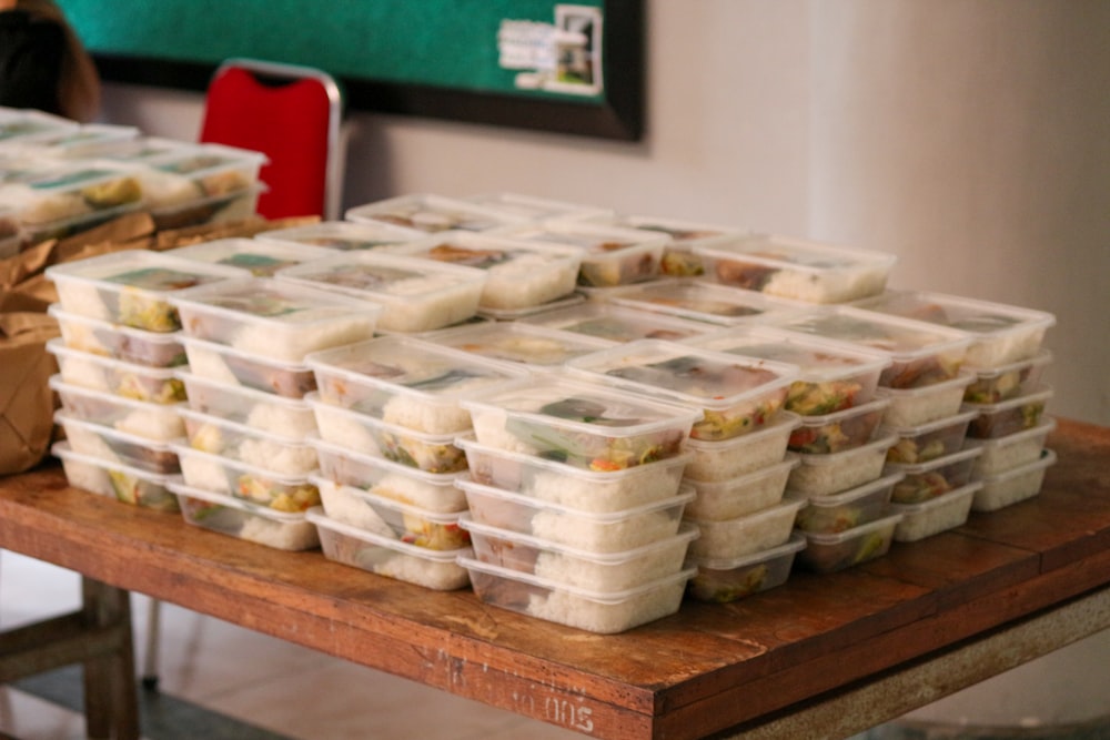 una mesa cubierta con recipientes de plástico llenos de comida