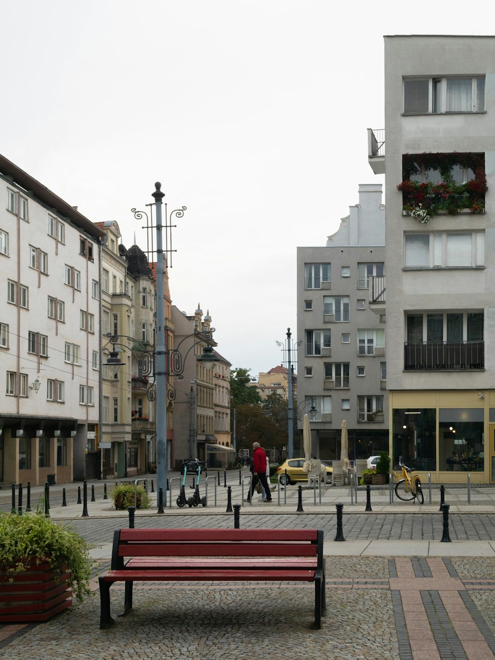 a red bench sitting on top of a cobblestone street