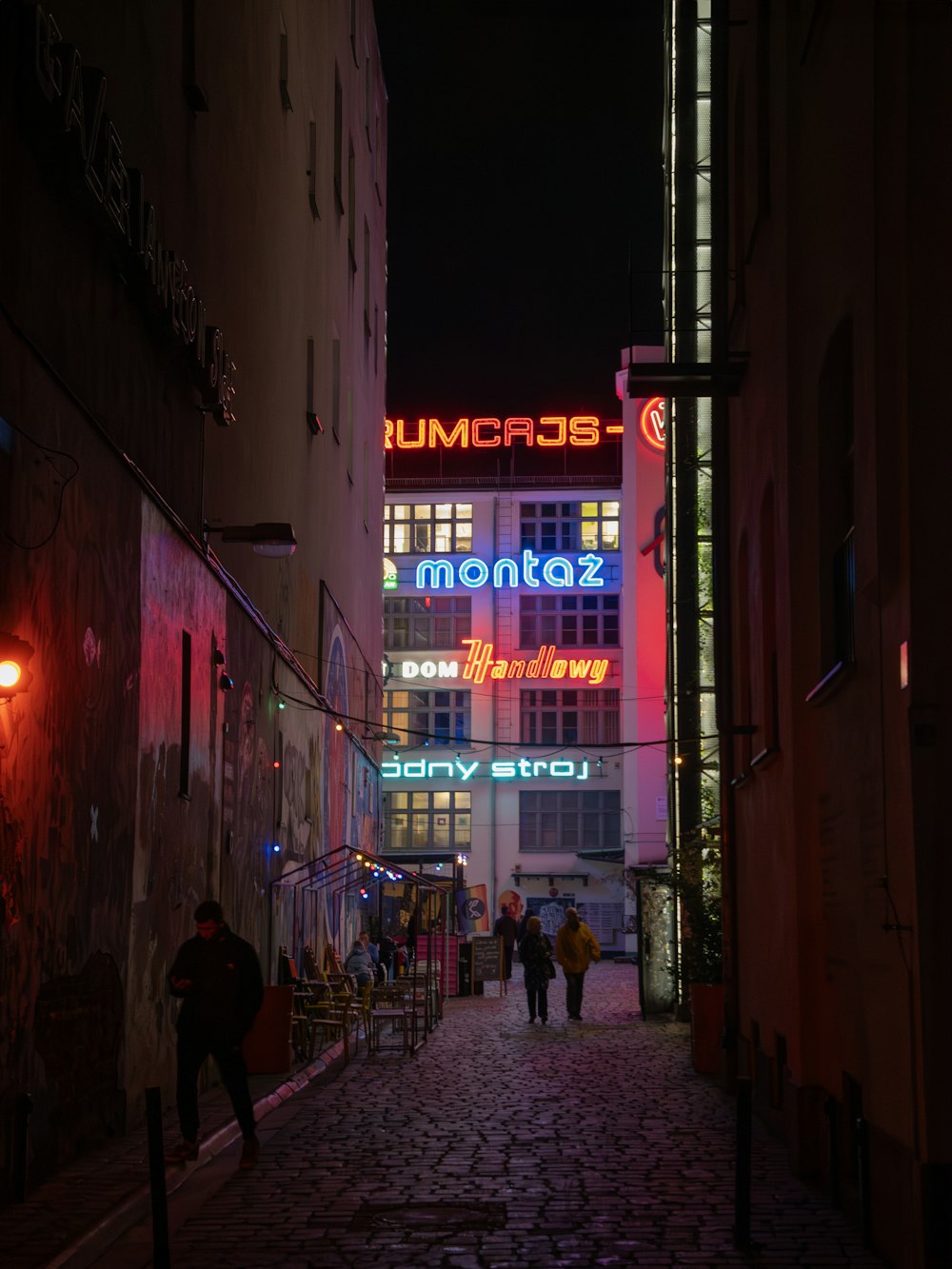 people walking down a cobblestone street at night