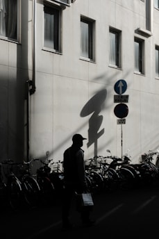 a man walking down a street next to a tall building