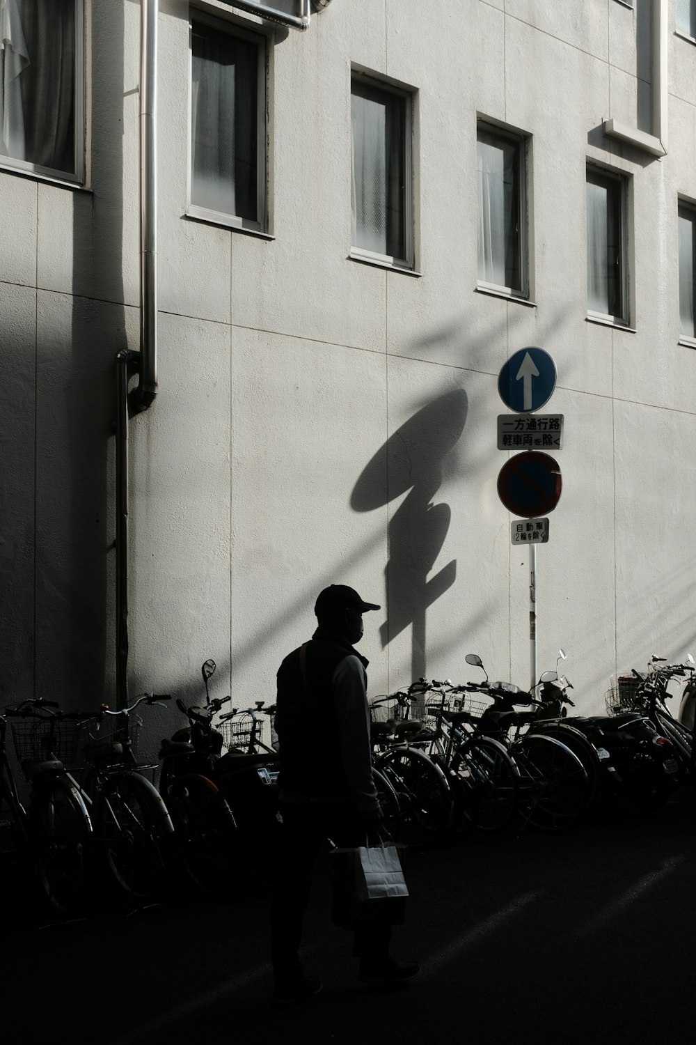 a man walking down a street next to a tall building