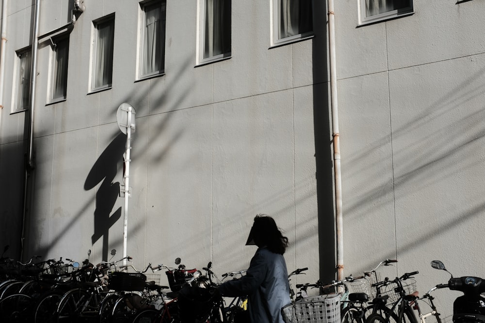 a woman walking down a street past a bunch of bikes