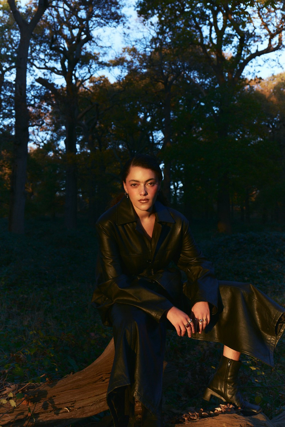 a woman sitting on a log in the woods