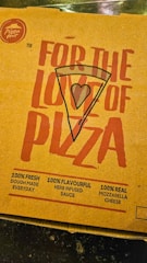 A pizza box lid with bold red text featuring the words 'For the love of pizza' and an illustration of a pizza slice with a heart symbol in the center. It includes promotional claims such as 100% fresh dough made every day, 100% flavorful herb-infused sauce, and 100% real mozzarella cheese. The Pizza Hut logo is visible in the top left corner.