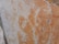 A close-up of a marble surface featuring intricate cracks and veining patterns in shades of orange, beige, and light gray. The texture appears smooth with natural imperfections, creating a visually interesting and organic design.