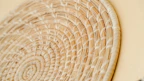 Artisan hands weaving natural fibers into a soft, textured basket.