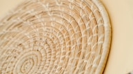 A close-up of hands weaving a basket using natural fibers, highlighting artisanal skill.