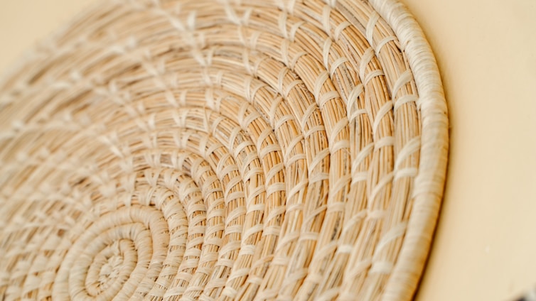 A close-up of artisan hands weaving colorful threads into a vibrant handmade basket.