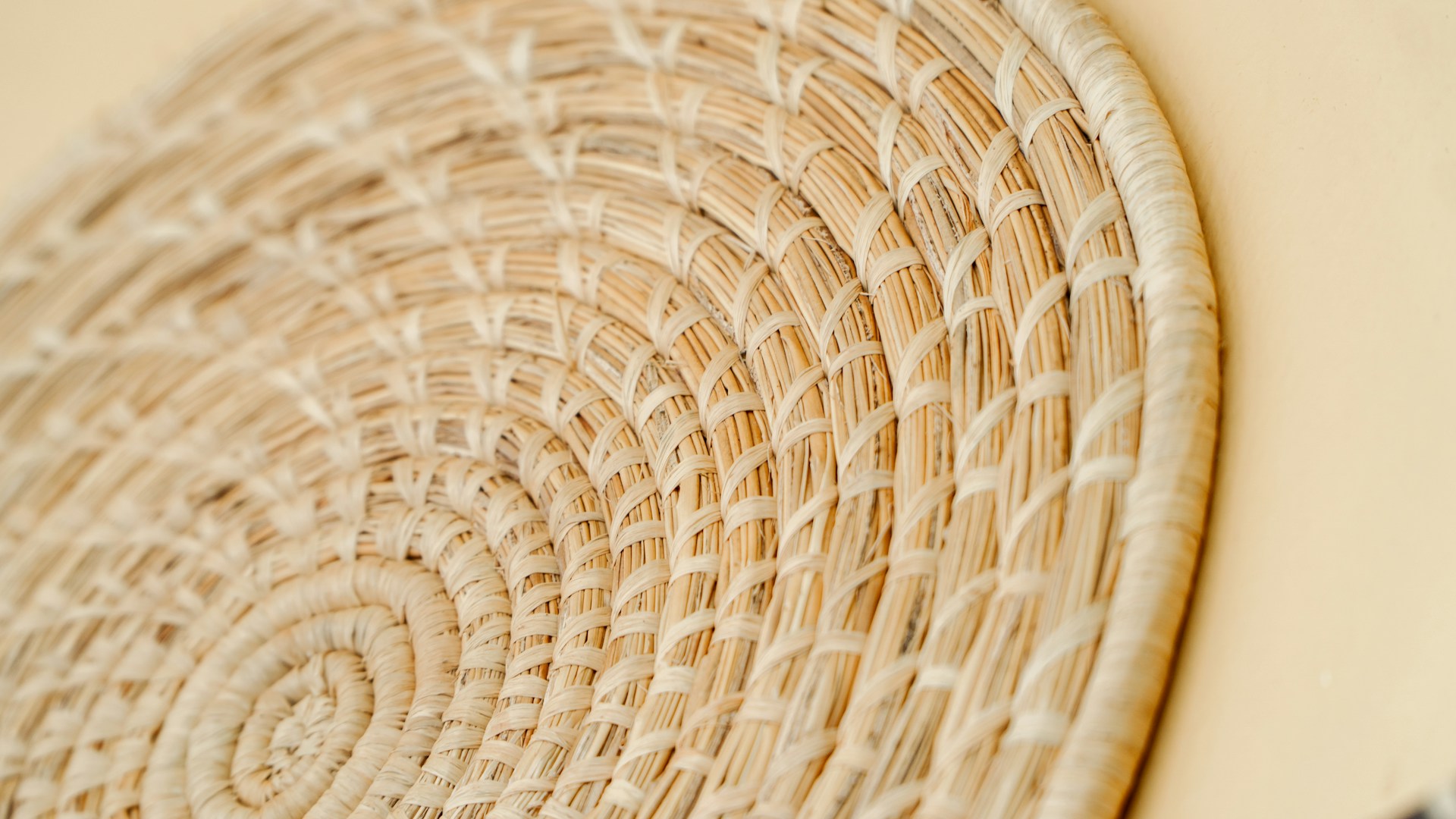 Close-up of a finely woven bamboo basket resting on a wooden table bathed in soft natural light, highlighting its intricate texture and warm earthy tones.