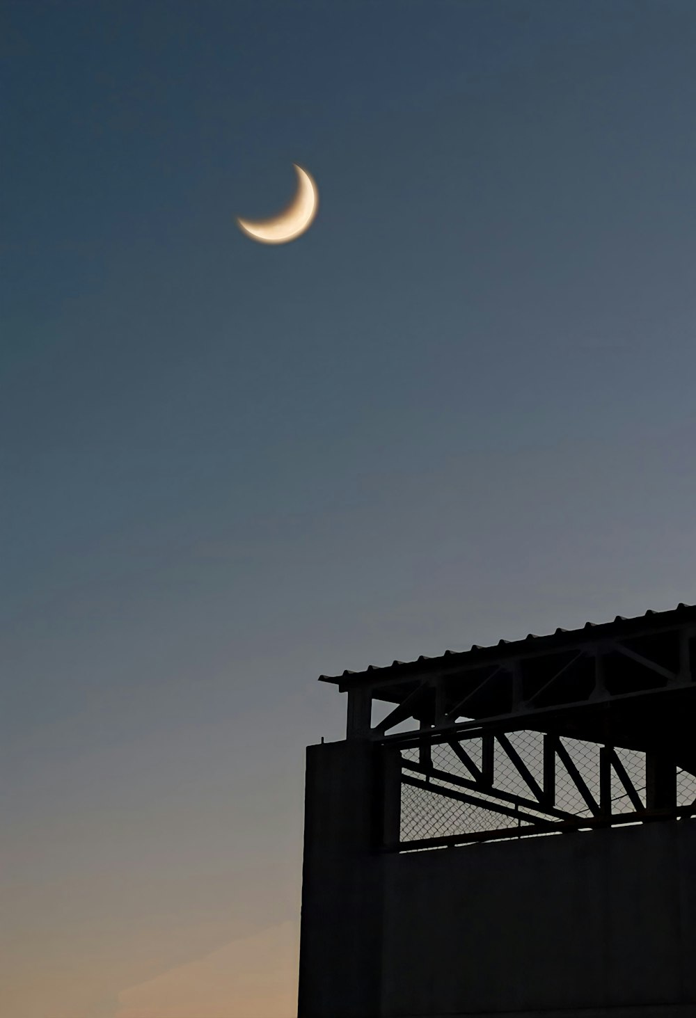 Se ve una media luna en el cielo sobre un edificio