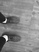 Close-up of sleek black sneakers with white soles on a wooden floor.