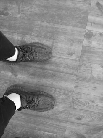 Close-up of sleek black sneakers on a modern wooden floor with soft natural lighting.