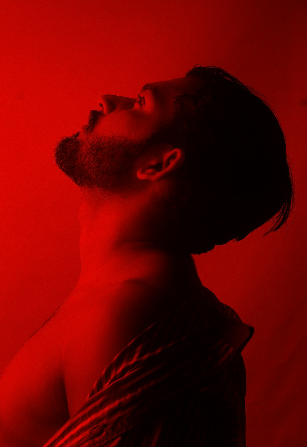 a man with his eyes closed standing in front of a red background