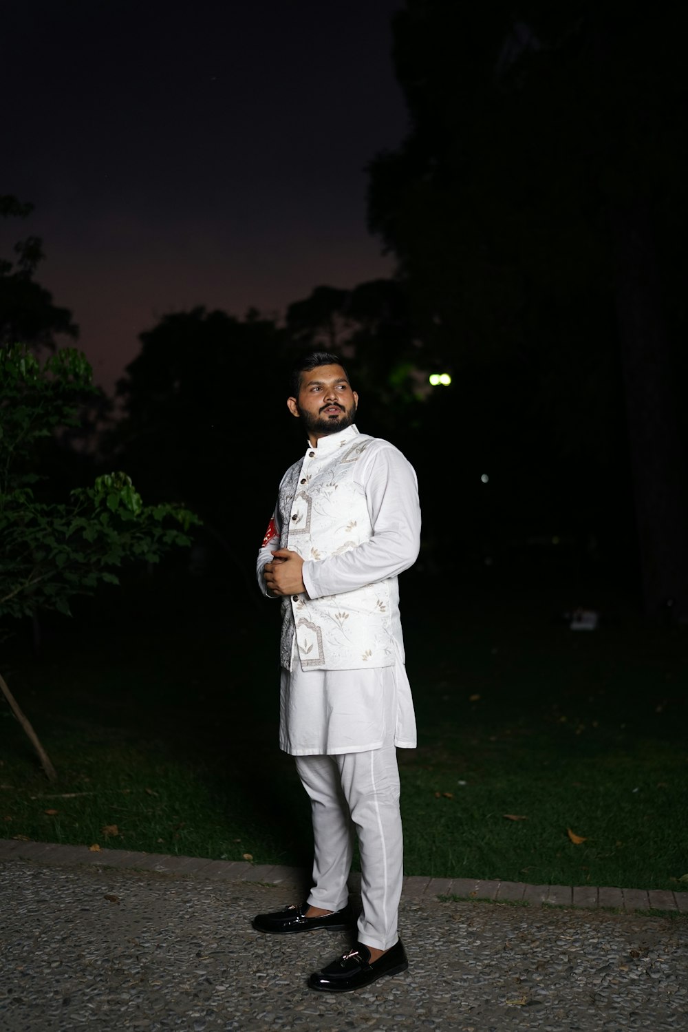 a man in a white suit standing in the dark