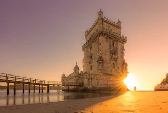 the sun is setting behind a tower on the beach