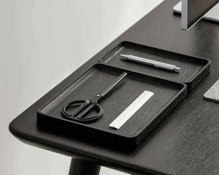 Contemporary 3D printed desk organizer in black with blue accents, holding pens and notes on a minimalist desk