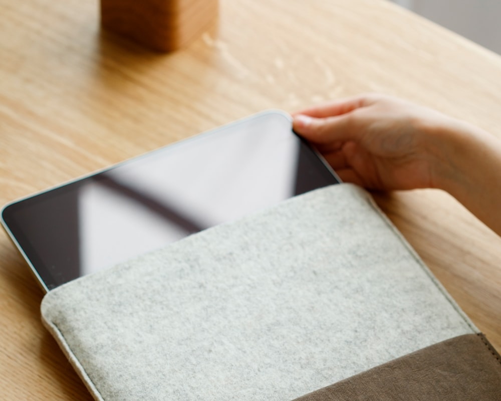 a person holding a tablet on a wooden table