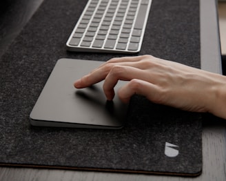 Close-up of hands typing on a sleek keyboard with a minimalist black and gray workspace background.