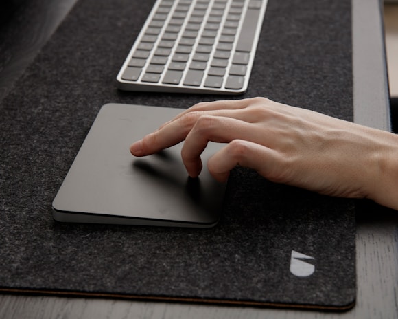 Close-up of hands typing on a sleek keyboard with a minimalist black and gray workspace background.