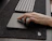 Close-up of a hand using a smart gadget on a minimalist dark desk.