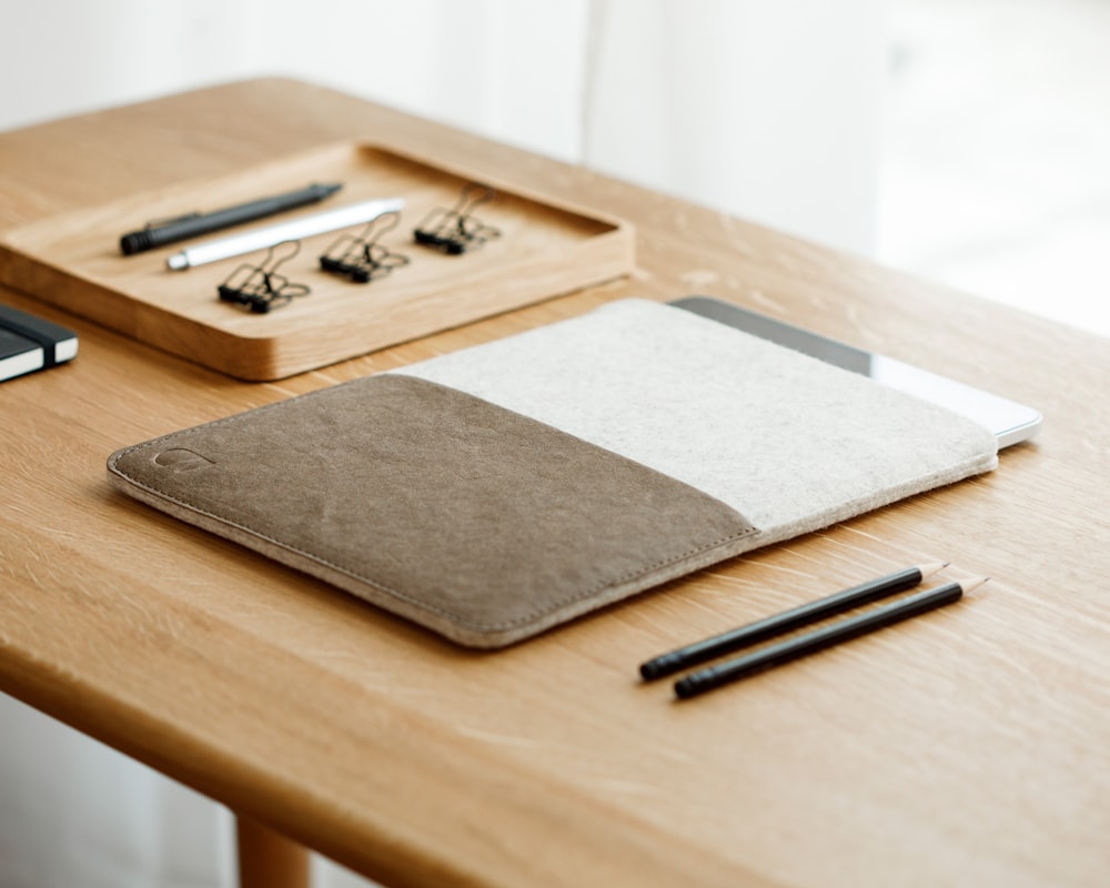 a wooden table topped with a notebook and pen