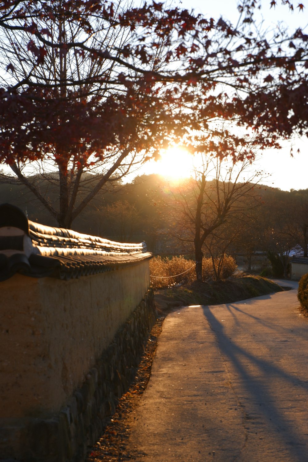 the sun is setting behind a stone wall