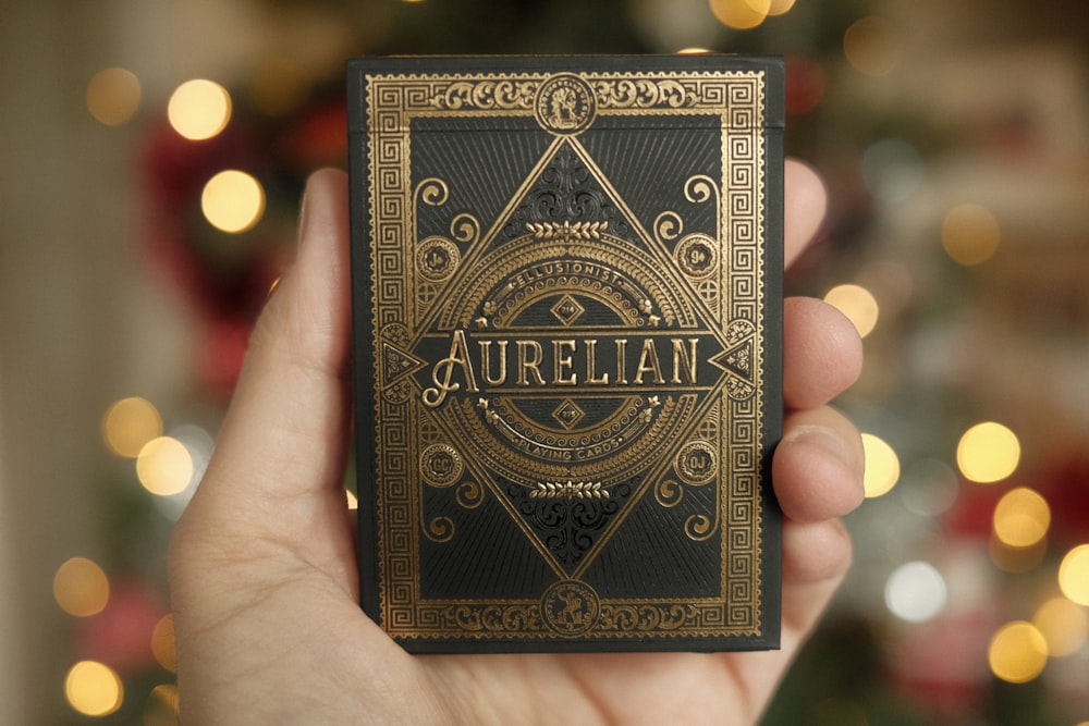 a hand holding a playing card in front of a christmas tree