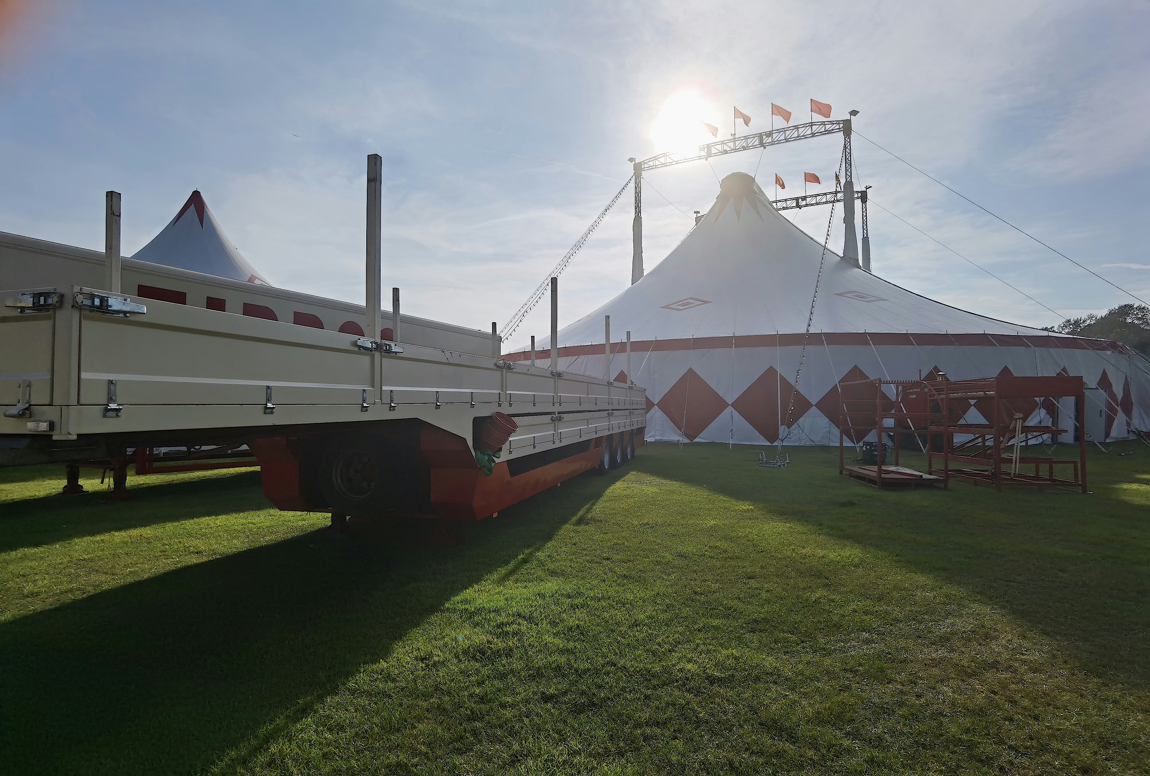 a large white truck parked on top of a lush green field