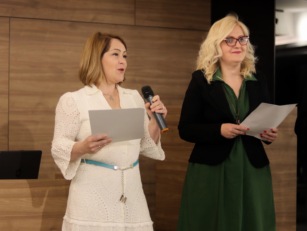 a woman standing next to a woman holding a microphone