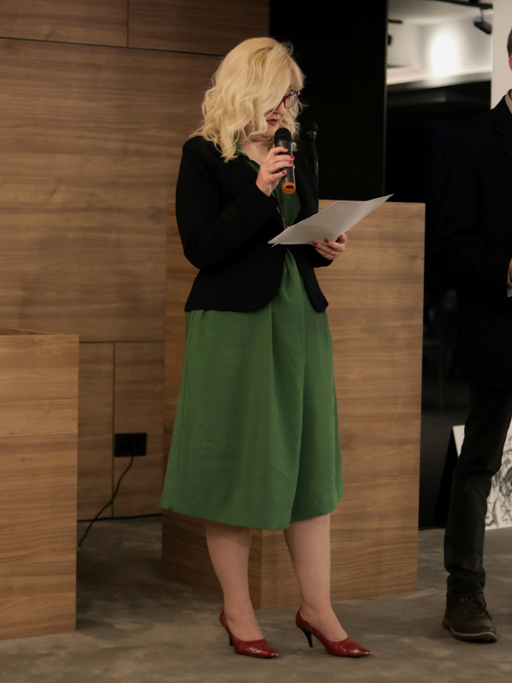una donna in un vestito verde che tiene in mano un microfono