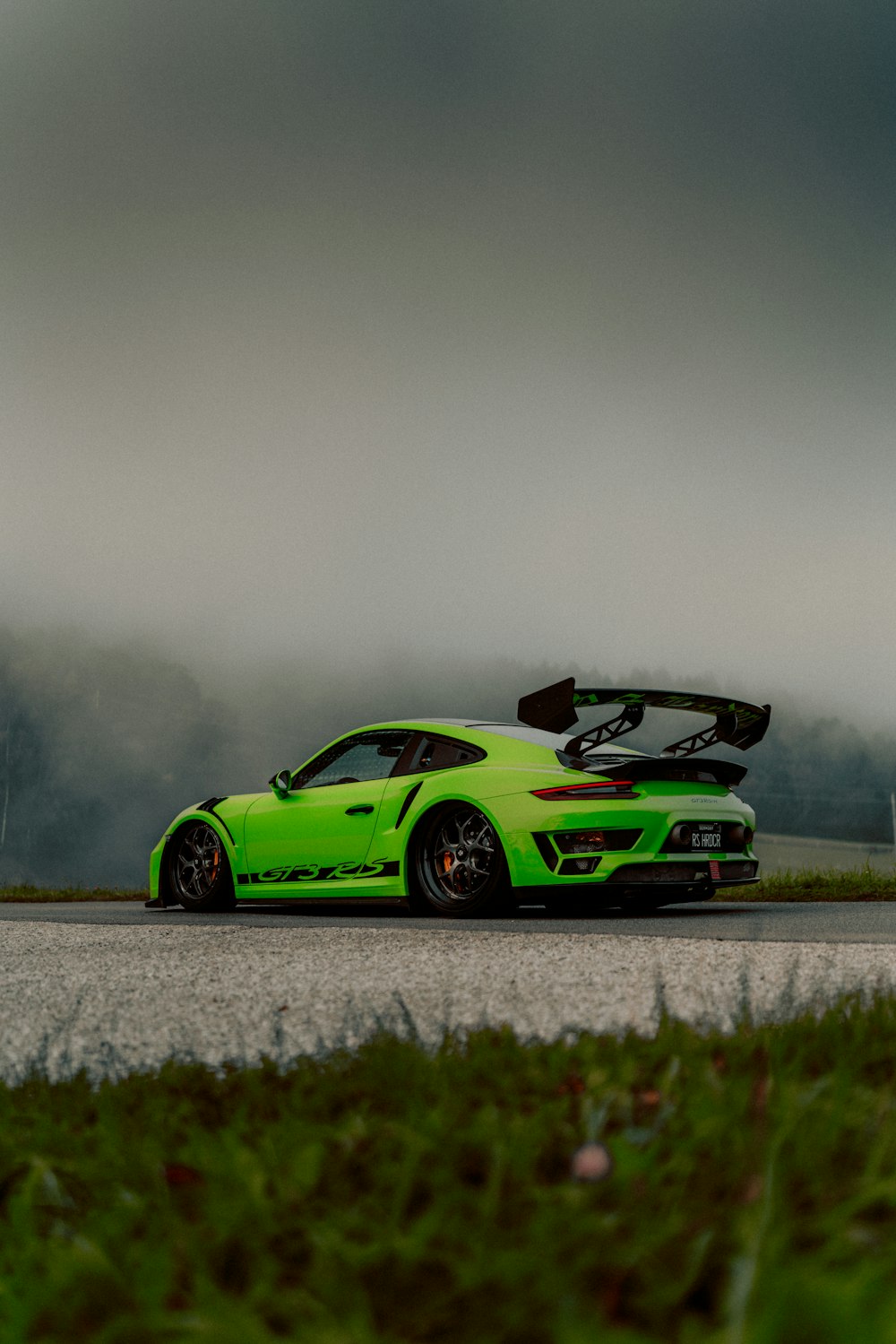 a green sports car driving down a road