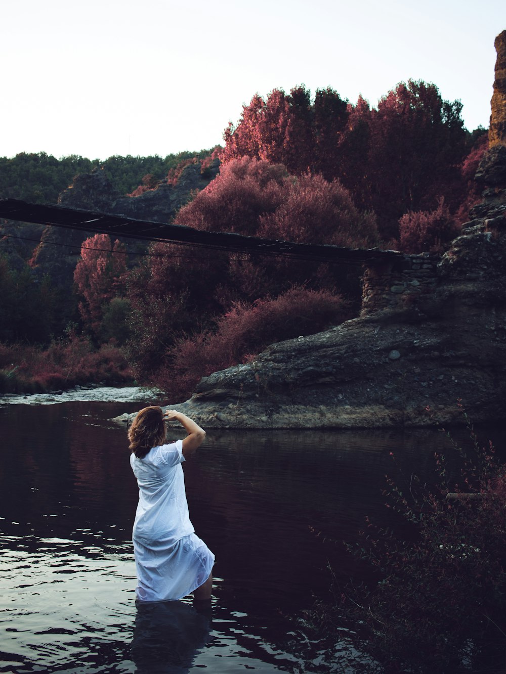 a woman in a white dress standing in a river