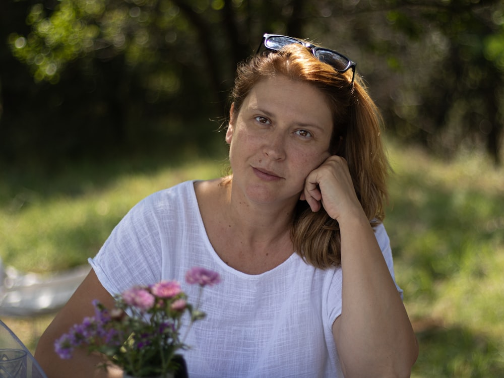 a woman sitting at a table with a vase of flowers