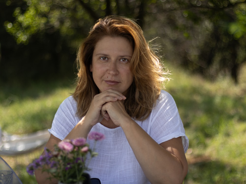 a woman sitting at a table with a vase of flowers