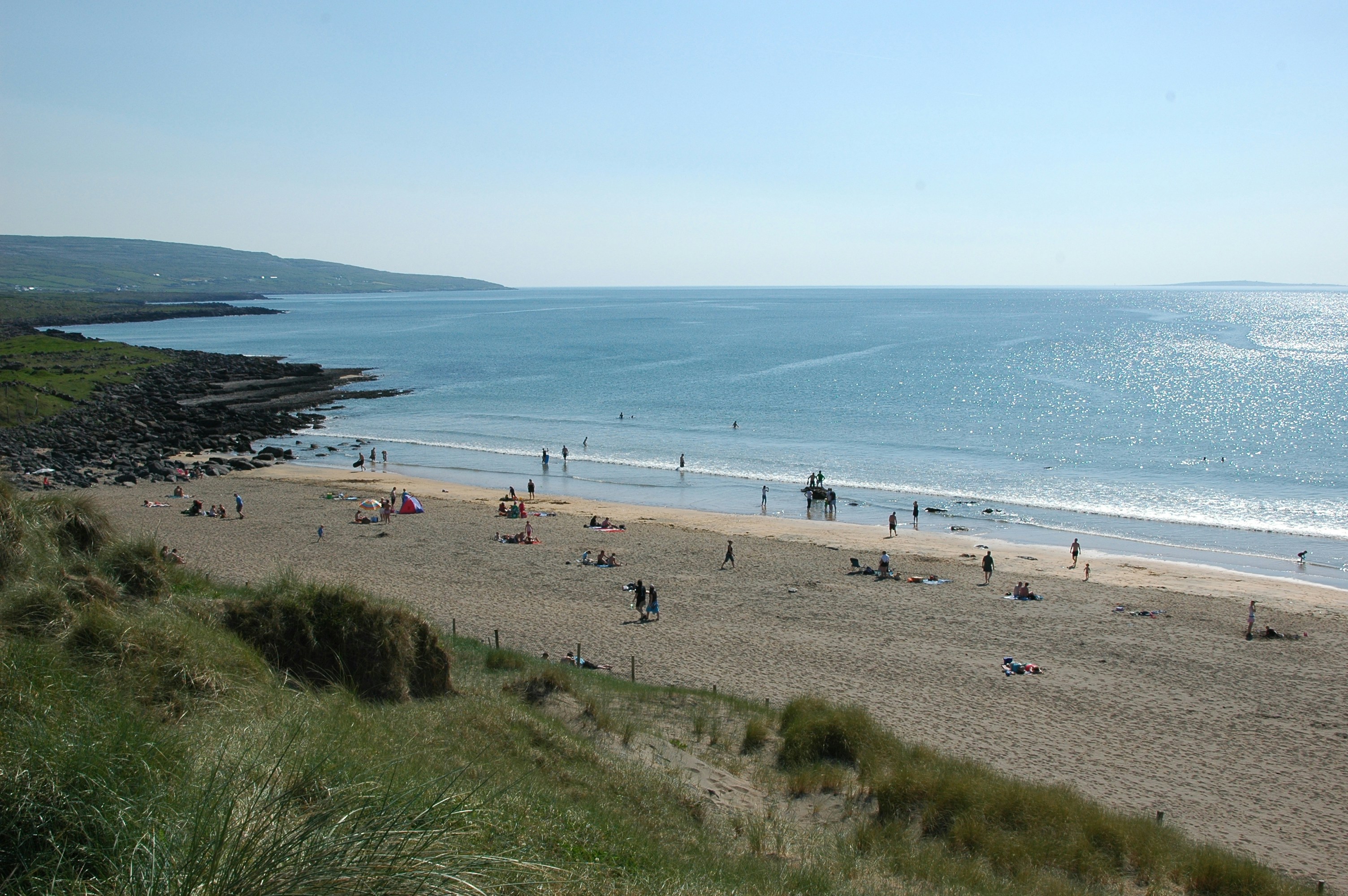 um grupo de pessoas em pé em cima de uma praia de areia