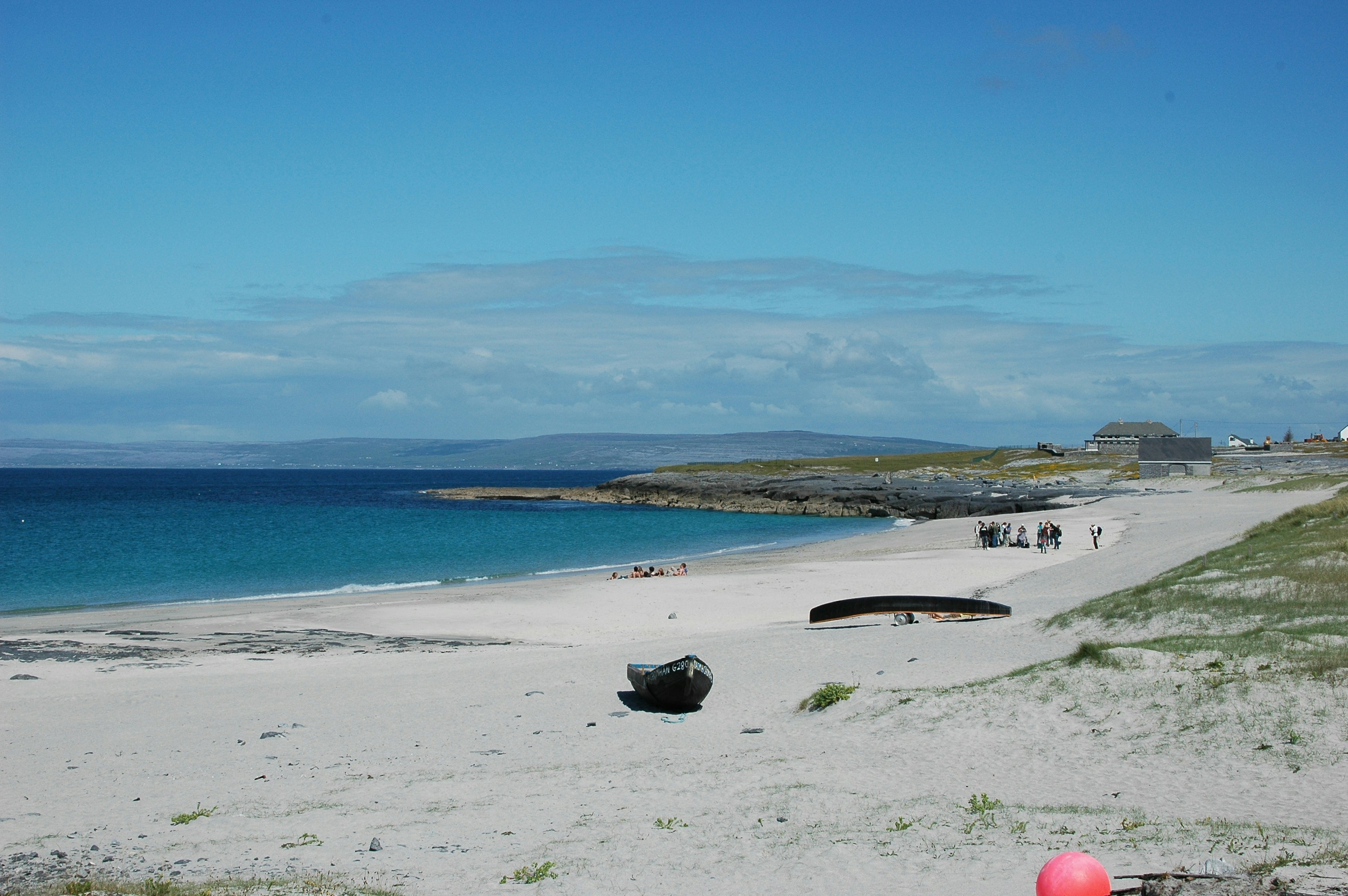 a beach with a boat on it and people walking on it