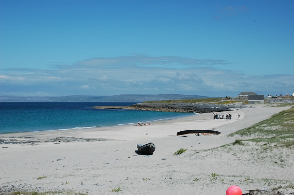 a beach with a boat on it and people walking on it