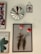 A collection of framed art pieces hung on a wall, including a decorative mirror with a scalloped edge. The main framed piece features two vibrant red tulips with a small toy mouse nestled between the stems. Other frames contain floral and abstract designs, one with text in French.