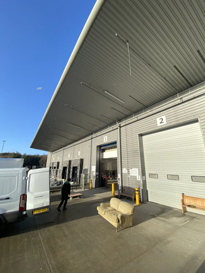 A professional mover carefully loading a large sofa into a sleek 12m³ moving van under a deep blue sky.