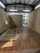 A partially constructed room inside a warehouse, featuring wooden floors and walls with exposed beams on the ceiling. Unfinished wooden frames are visible on the floor, with some construction tools in the background.