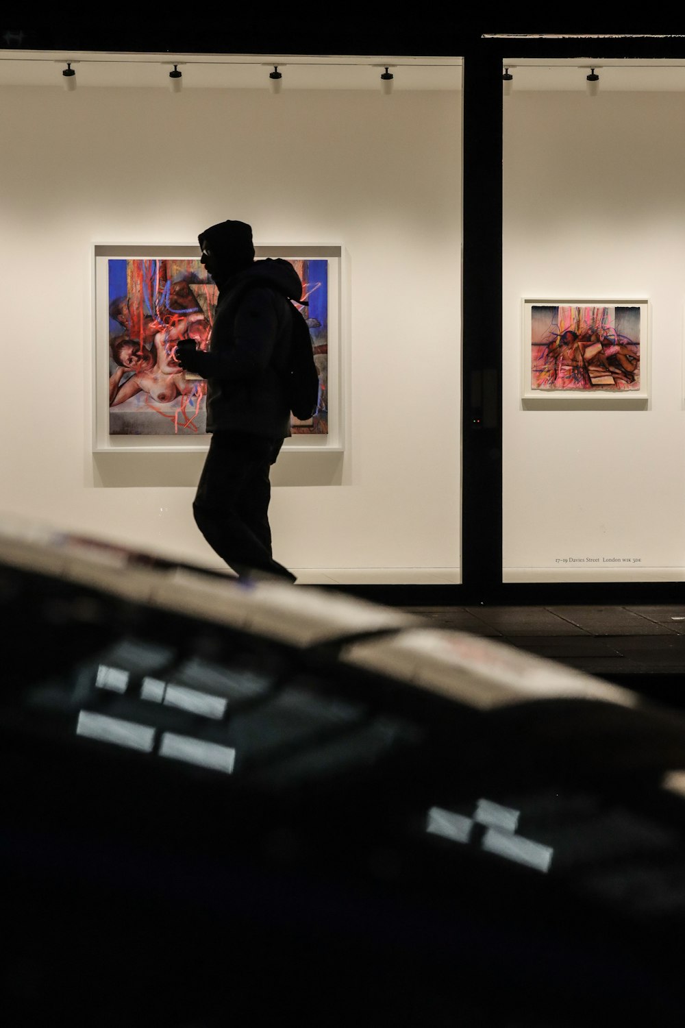 a man walking past a couple of paintings on display