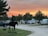 RV parked beside a gazebo with horseshoes set up and wildlife visible in the background at sunset.