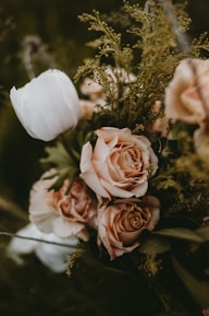 Close-up of a romantic bouquet blending soft clay and blush beige flowers with charcoal accents.