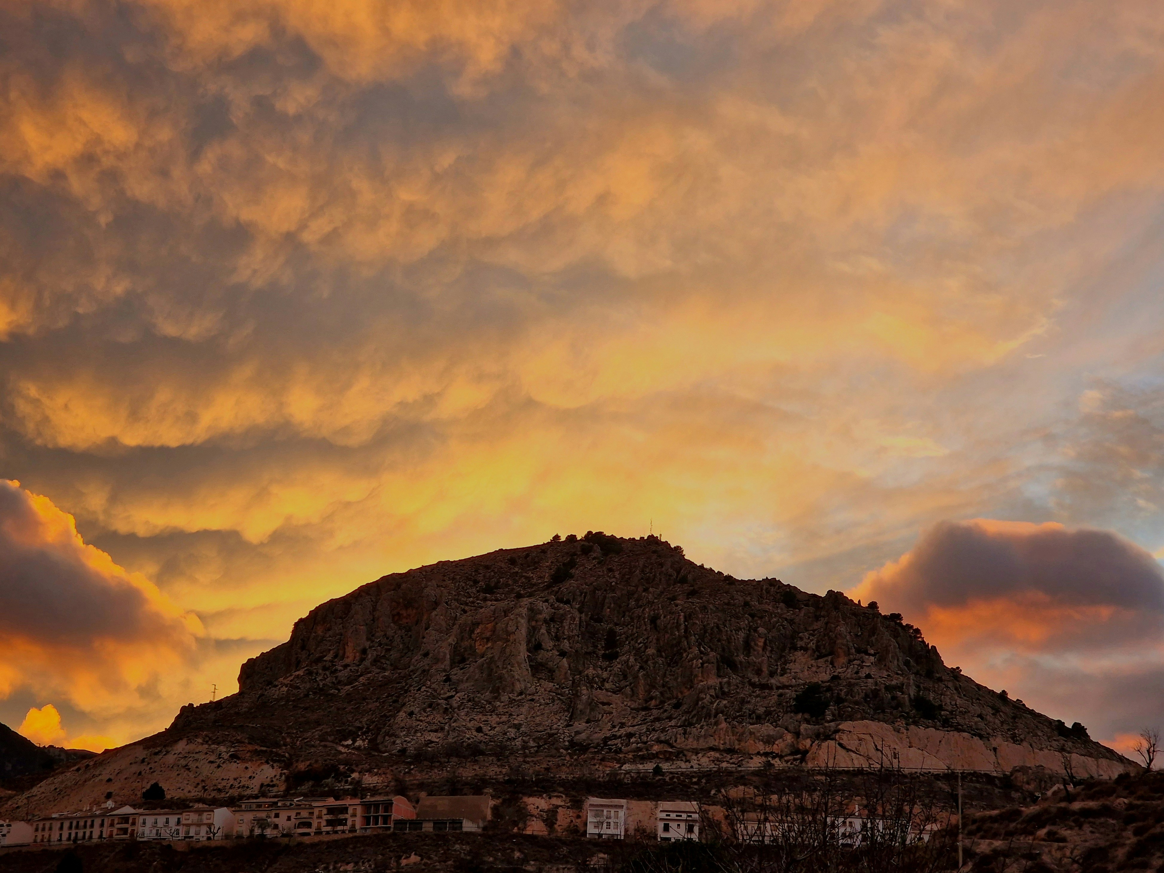 a mountain with a sky filled with clouds