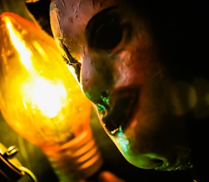 Close-up of a realistic biscuit head sculpture glowing under neon lilac light on a black background.