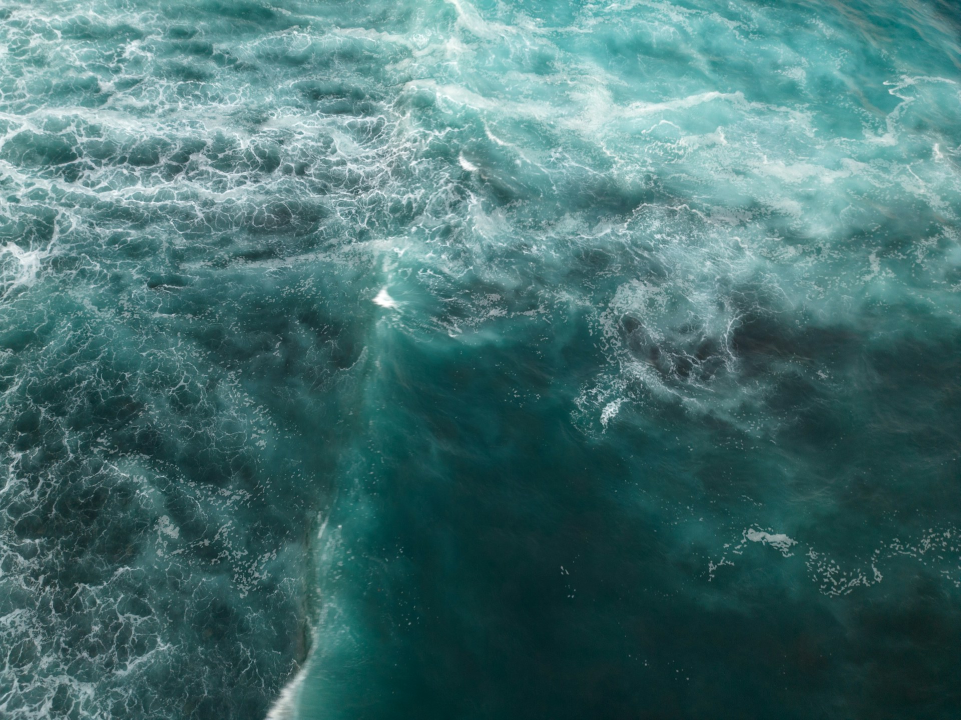 A dramatic satellite view of a swirling tropical cyclone forming over the ocean, with clouds spiraling over deep blue waters.