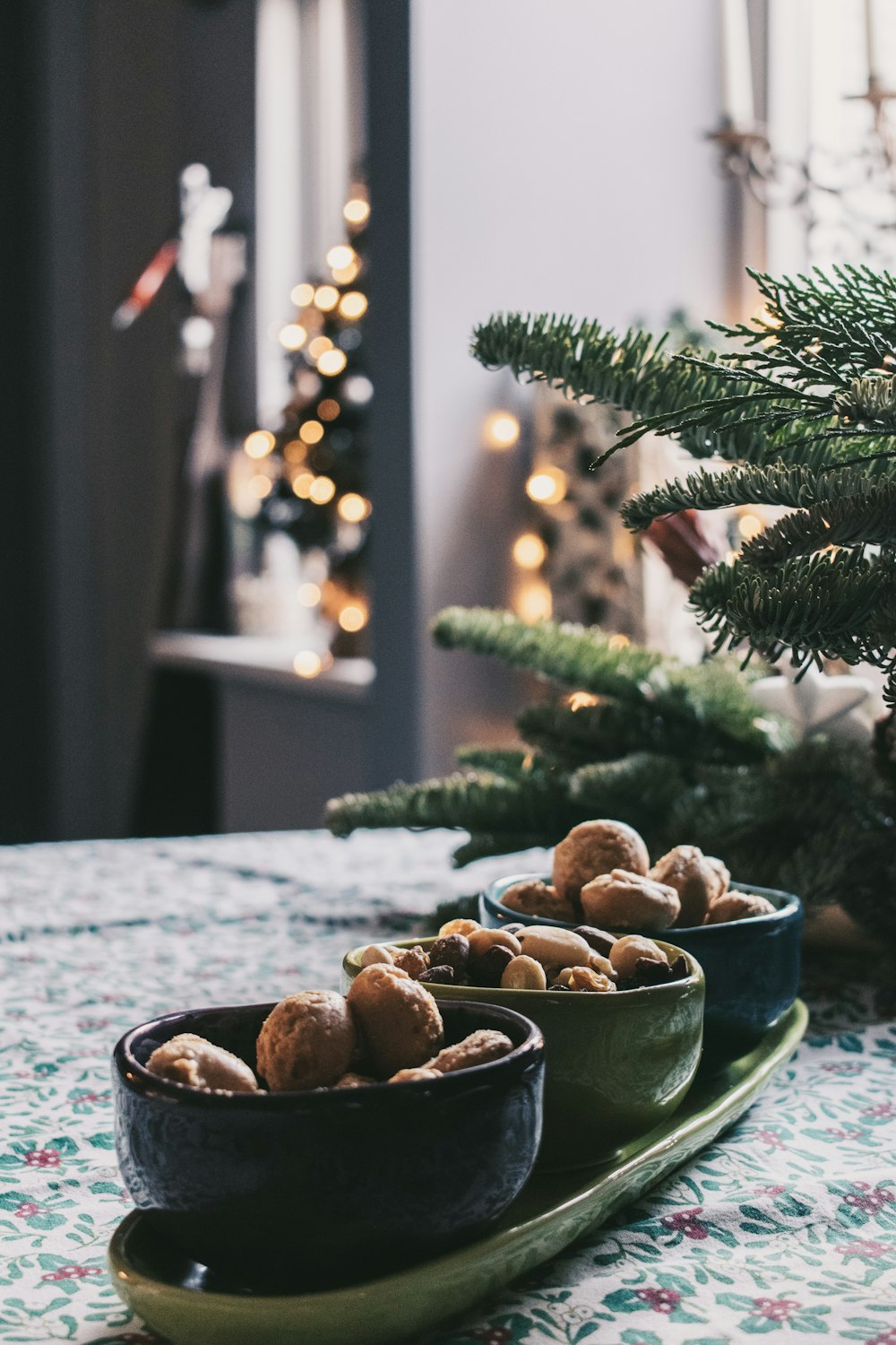 three bowls of nuts on a table with a christmas tree in the background