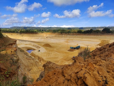 Heavy machinery extracting basalt rock at a rugged quarry site under a clear sky.