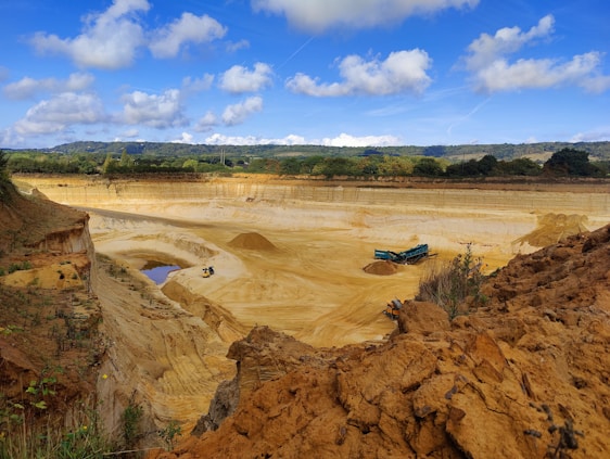 A rugged quarry site with workers extracting large blocks of natural stone under a clear blue sky.