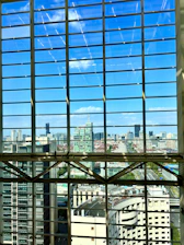 A detailed architectural blueprint spread out on a desk with a city skyline visible through the window.